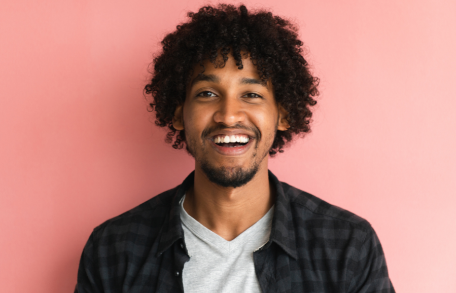 Mixed race smiling man standing against pink background