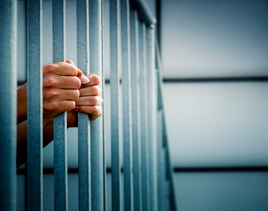 man holding bars in prison