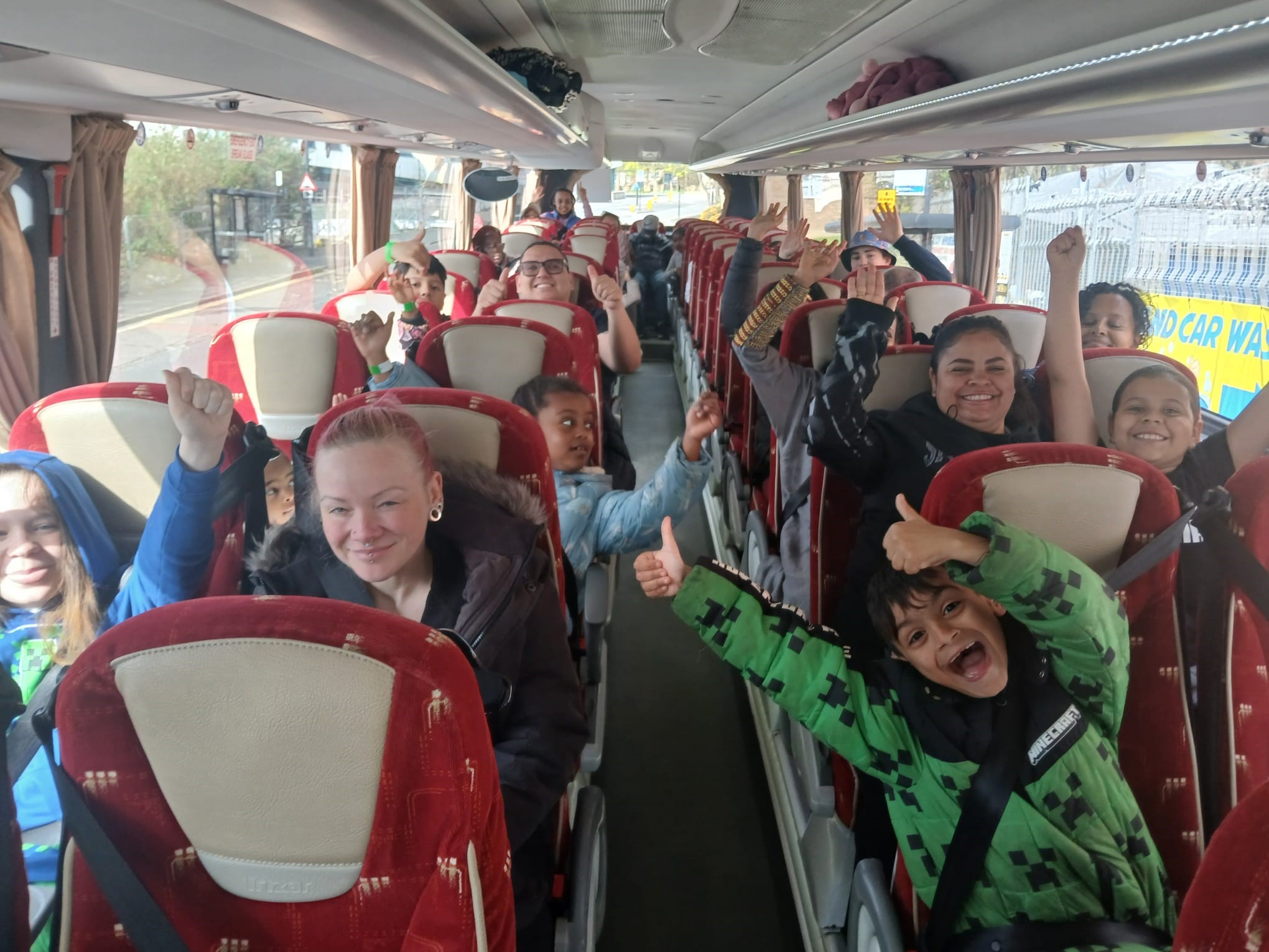 Kids and adults smiling on a bus.