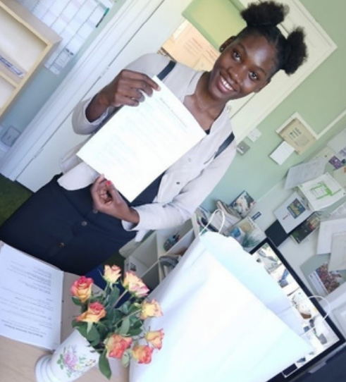 Young woman holding up certificate.