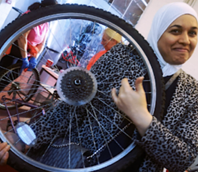 Woman holding up a bicycle wheel.