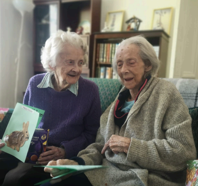 Two elderly ladies sitting down with Easter cards.