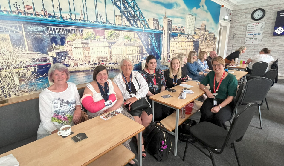 A group of women sitting in the Newcastle Deaf Centre near some tables.