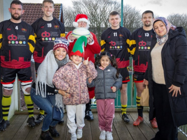 Group standing with Santa and rugby players.