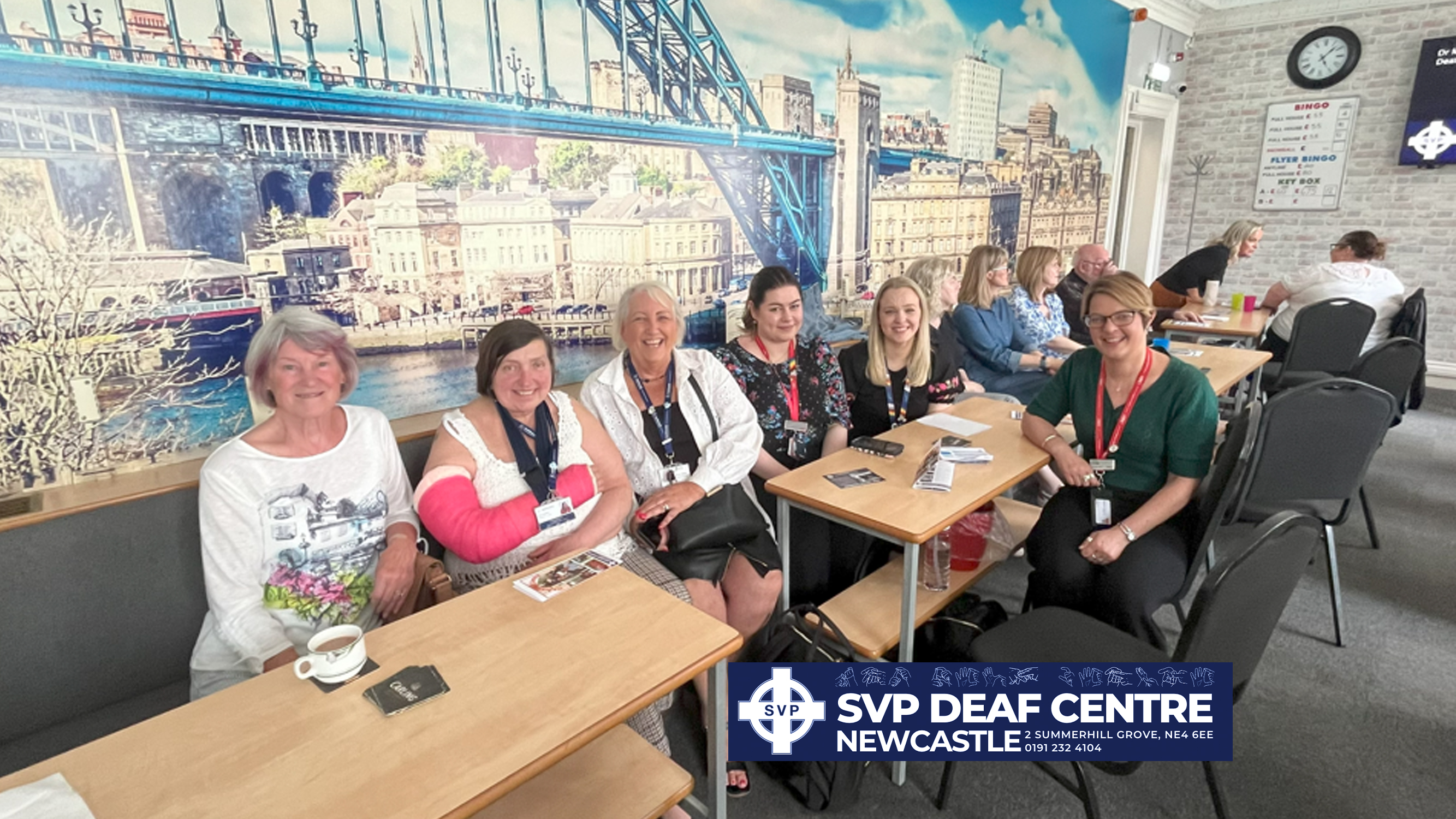 A group of women sitting in the Newcastle Deaf Centre near some tables.