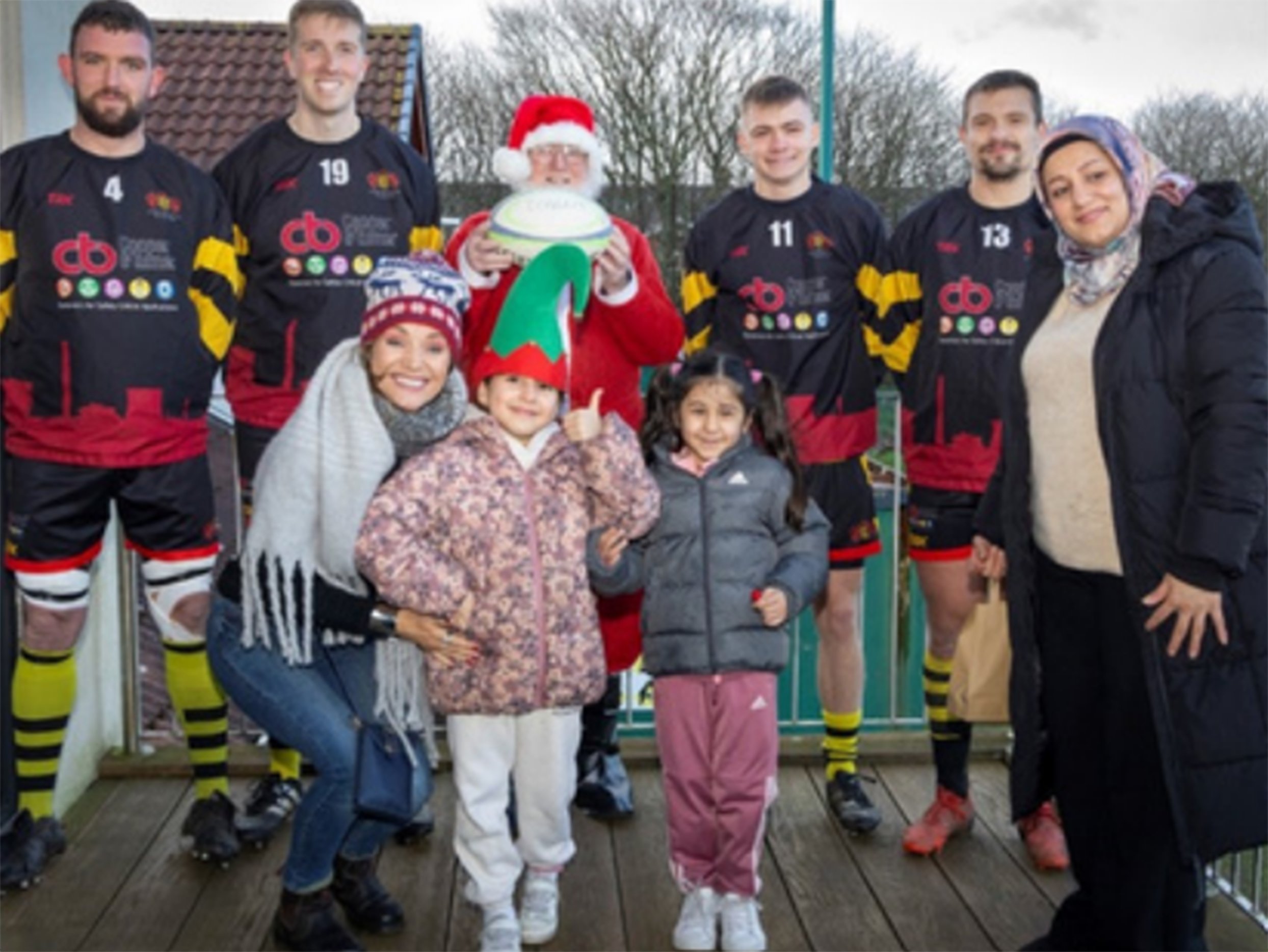 Group standing with Santa and rugby players.