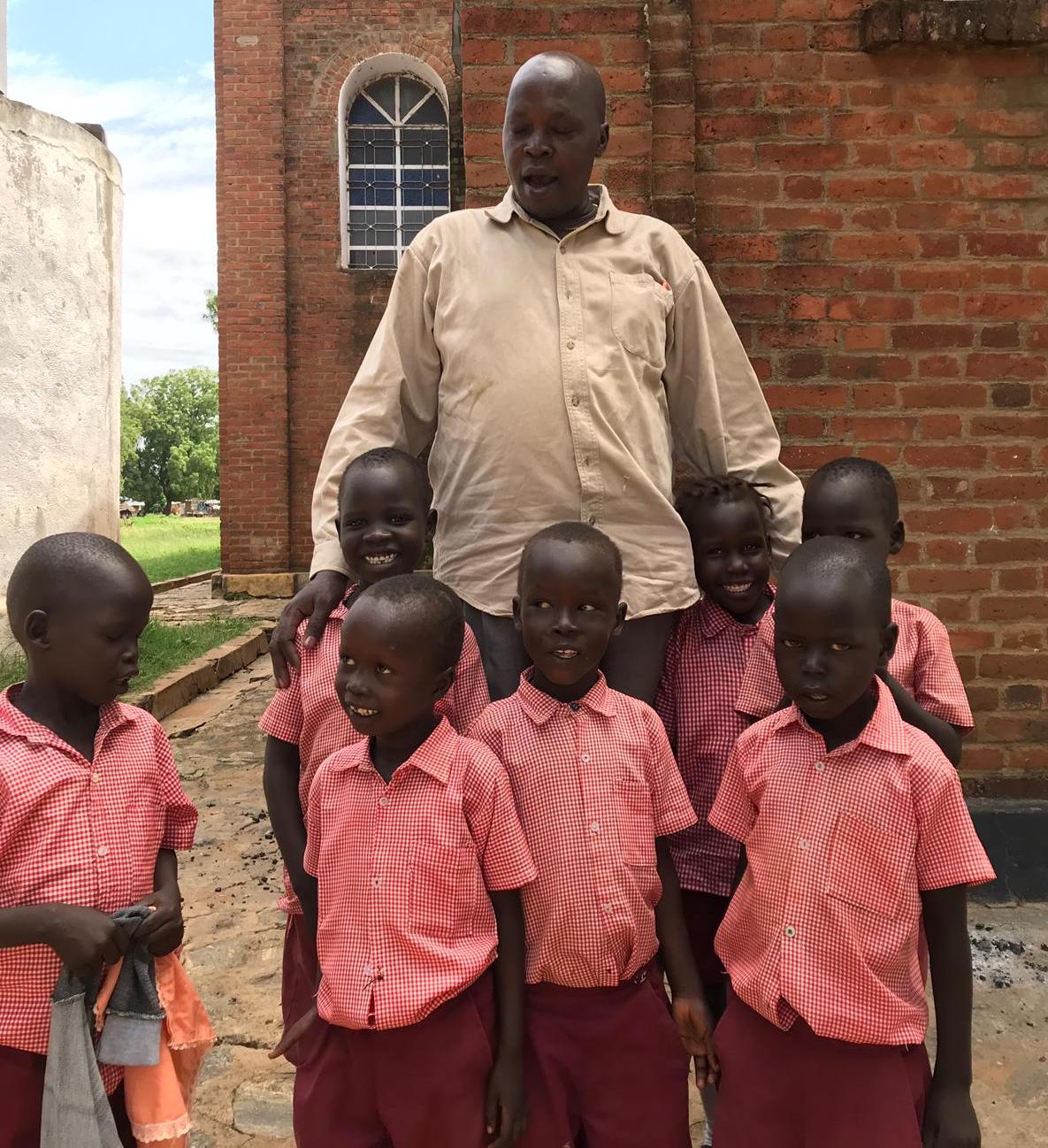 man standing with primary school kids in uniform