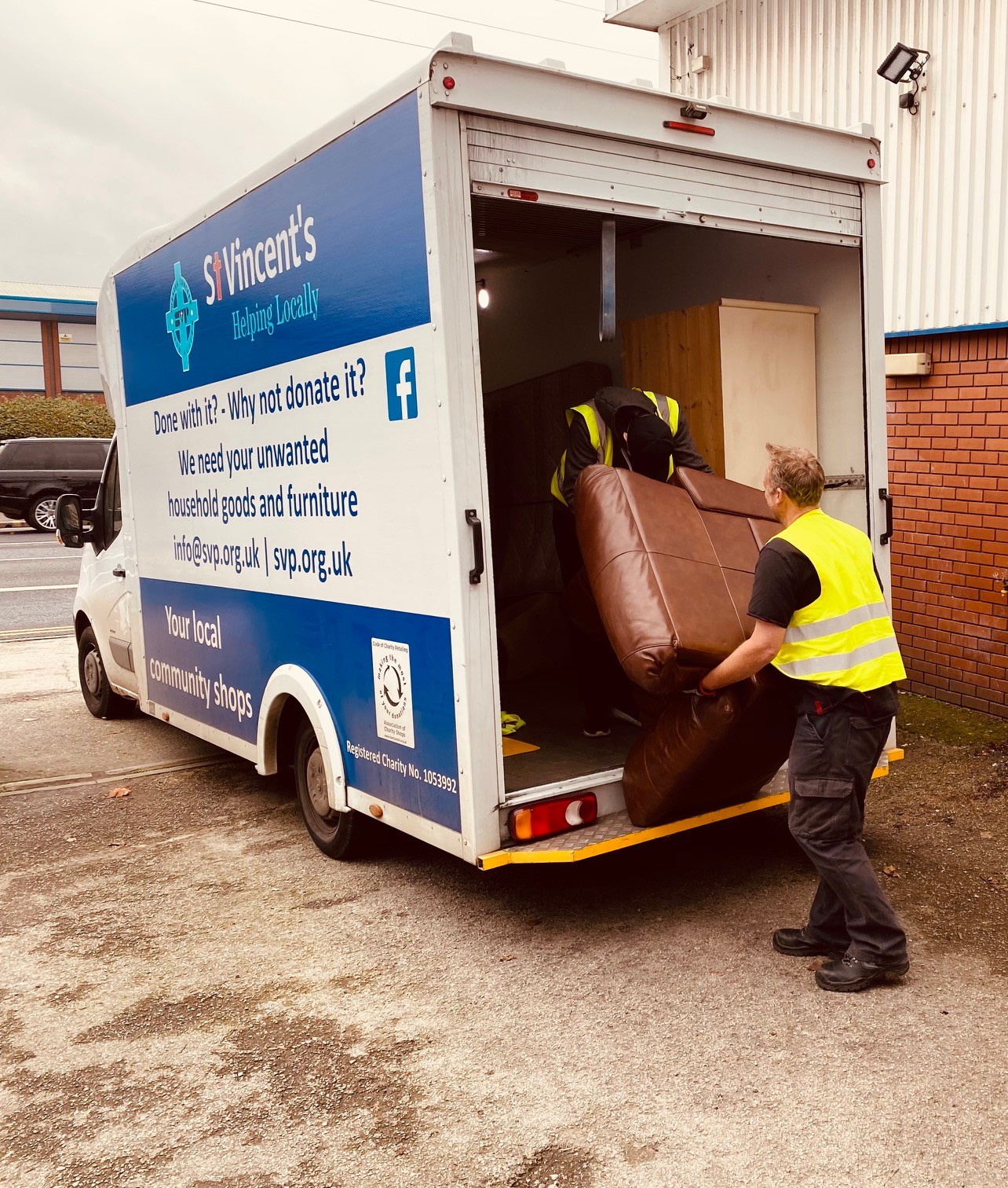 A member of staff and a volunteer loading a box van with a furniture delivery.