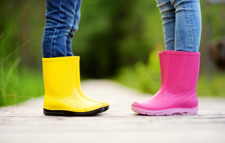 Legs of pair of children facing each other in yellow and pink wellies