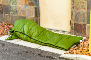 rough sleeper in green sleeping bag on street