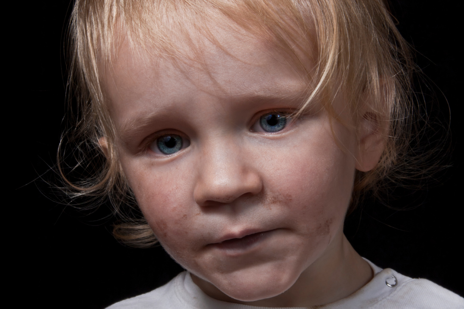 Blonde blue-eyed boy with dirty face and unkempt hair