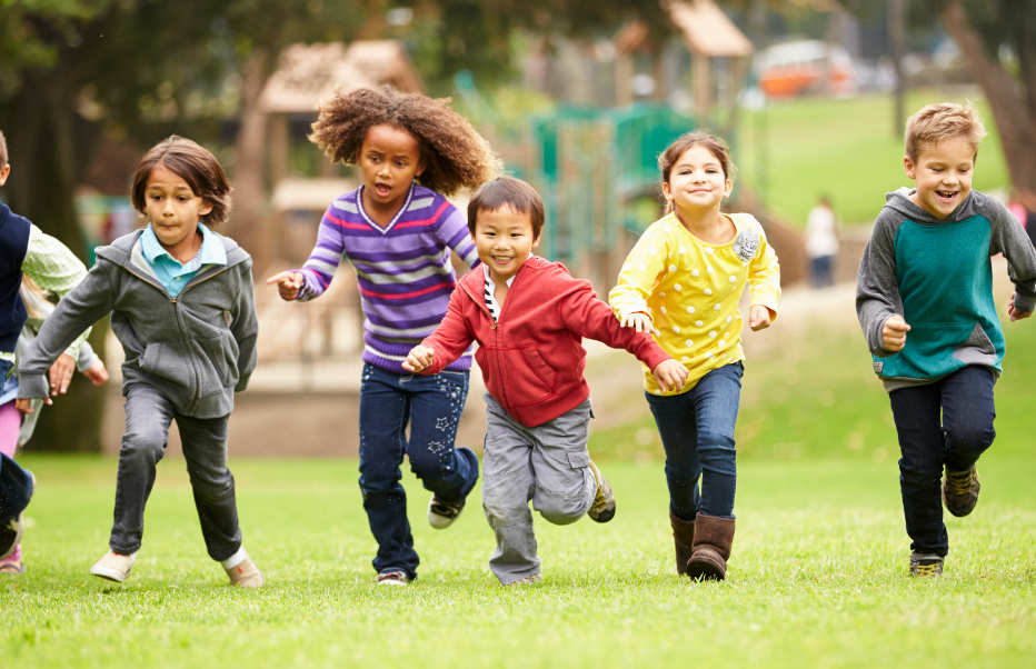 Children of different ethnicities running towards camera in a playground