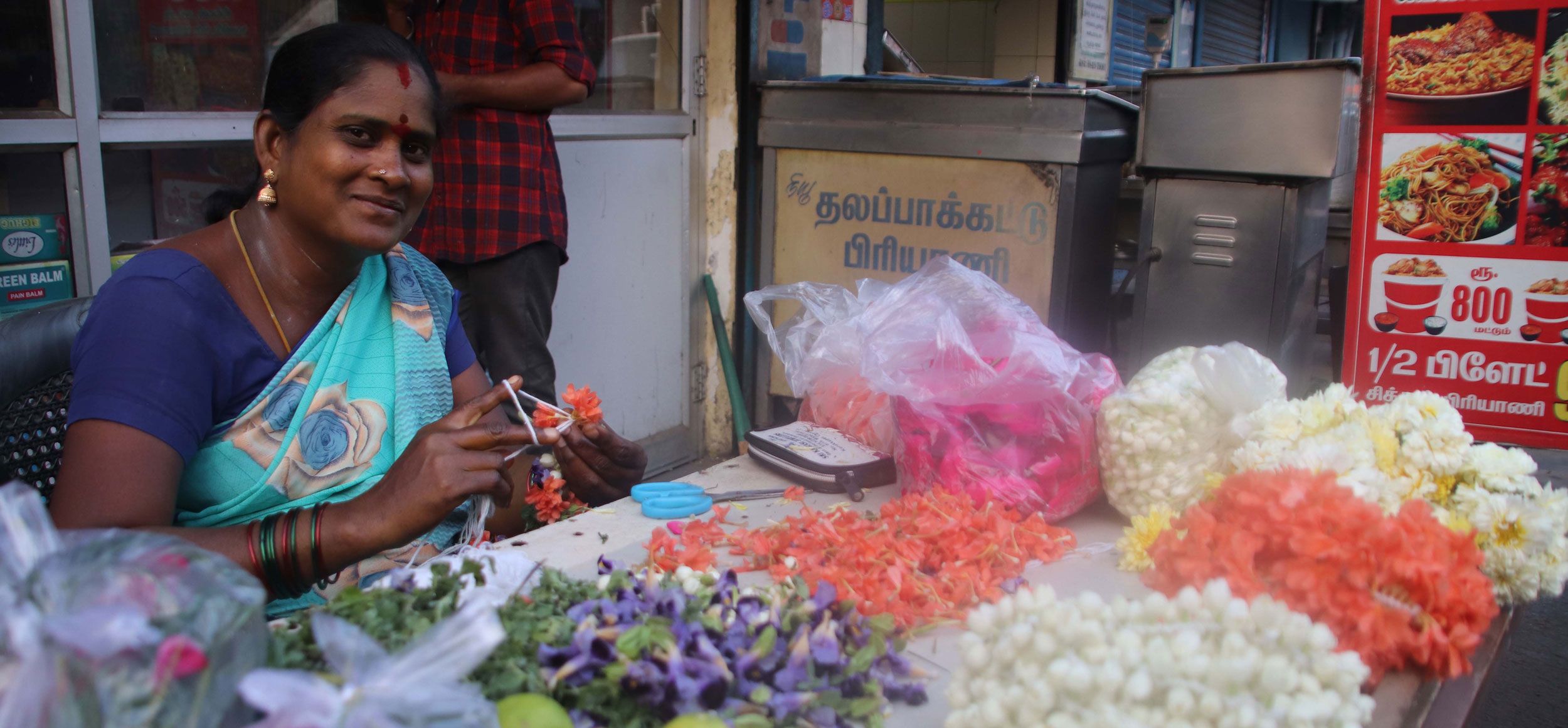 woman in sari selling food at stall