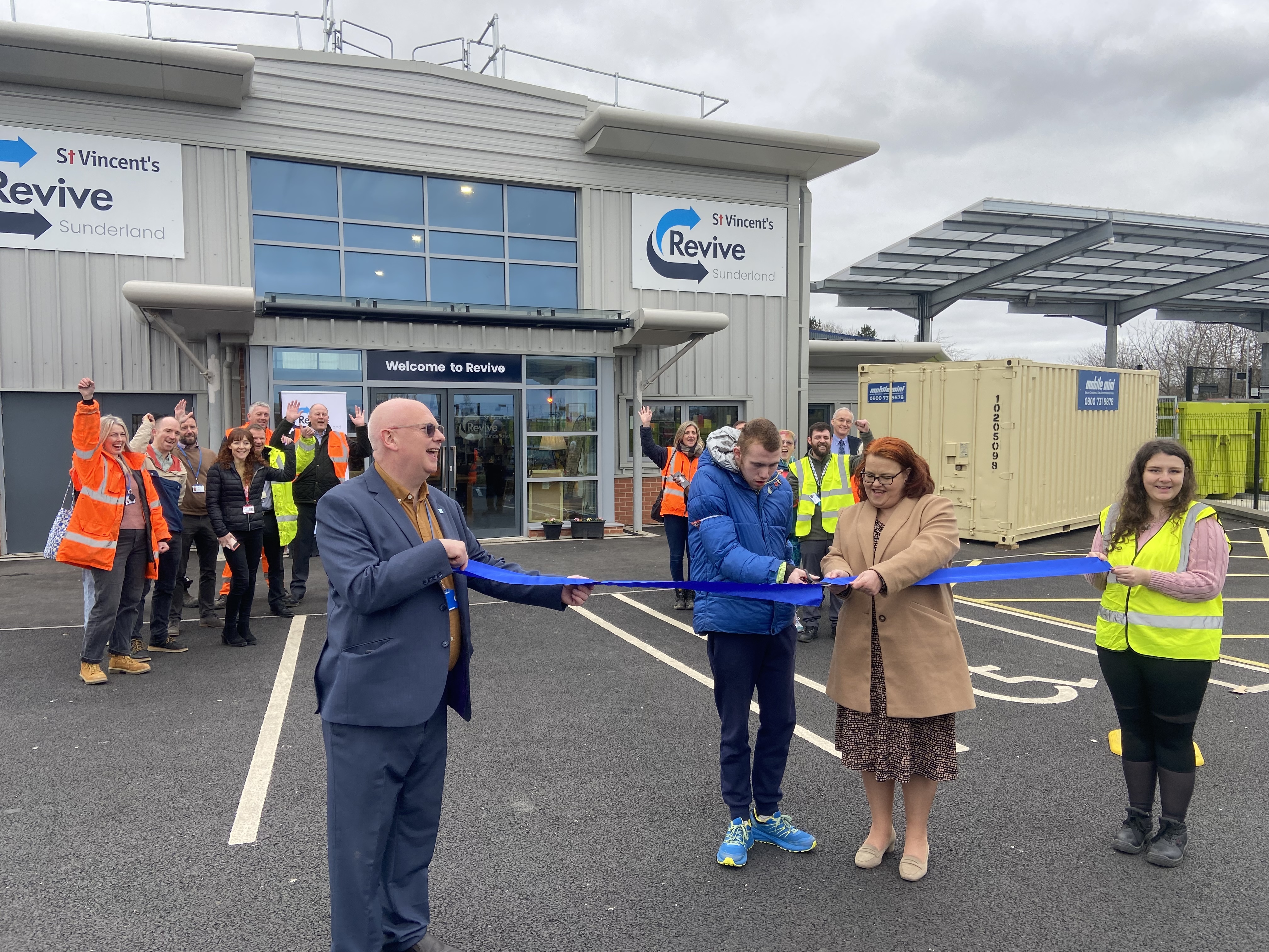 woman in beige cutting ribbon outside modern building 