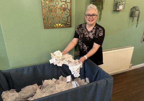 raffle draw - woman with box full of tickets looking happy